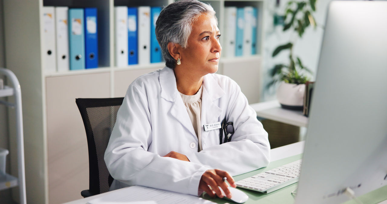 Computer, woman and doctor thinking with report in clinic for online research, diagnosis or treatment. Tech, medical service and female healthcare worker with internet for prescription in office