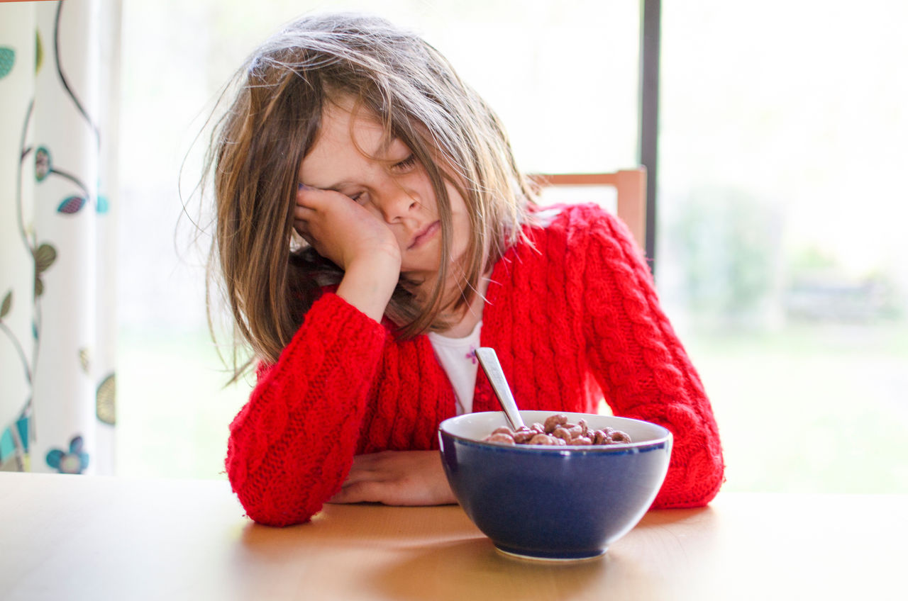 A tired child sleeps at the breakfast table