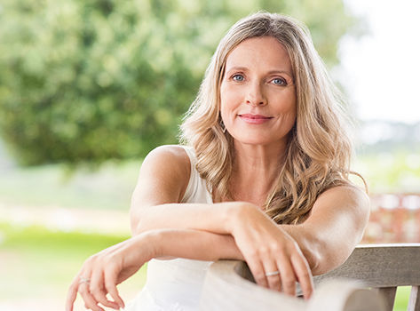 A woman with a healthy heart sits on a park bench and smiles.