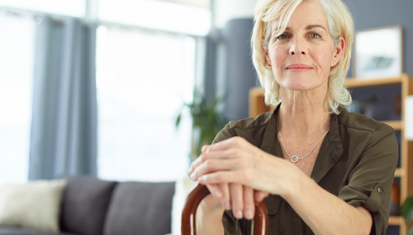 Woman sitting down with a cane in her hand.