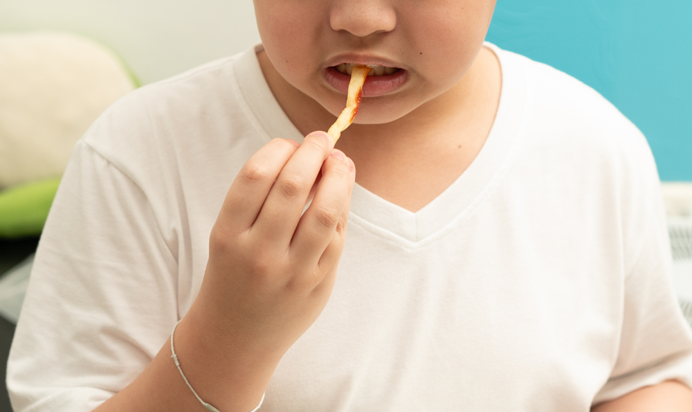 A child eats an unhealthy french fry.