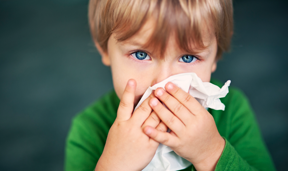 A child covering their mouth with a tissue