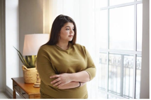 Woman looks through her window.