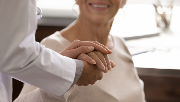 A patient holding hands with a doctor is shown.