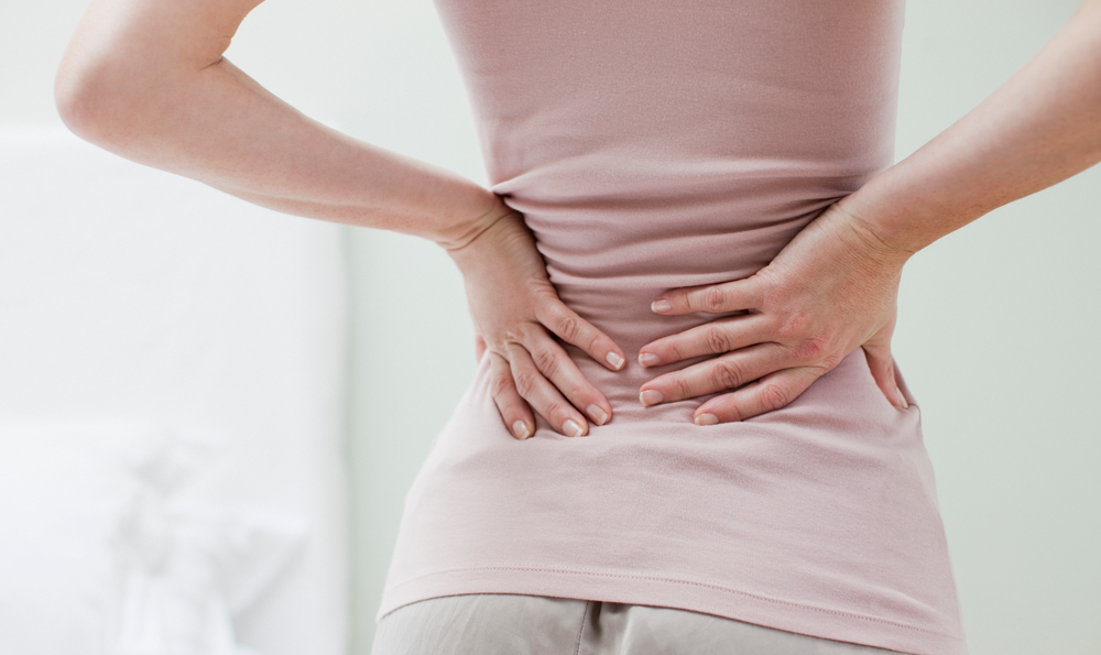 Woman grasps her spine in a spasm of back pain.