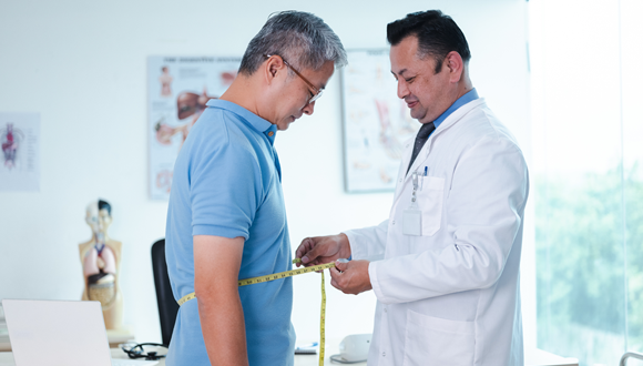 A doctor taking a measurement of a patient's waist is shown.
