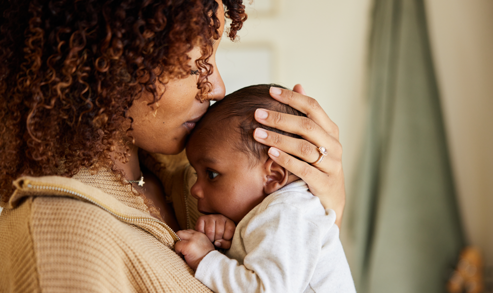 A mother kissing her baby on the forehead.