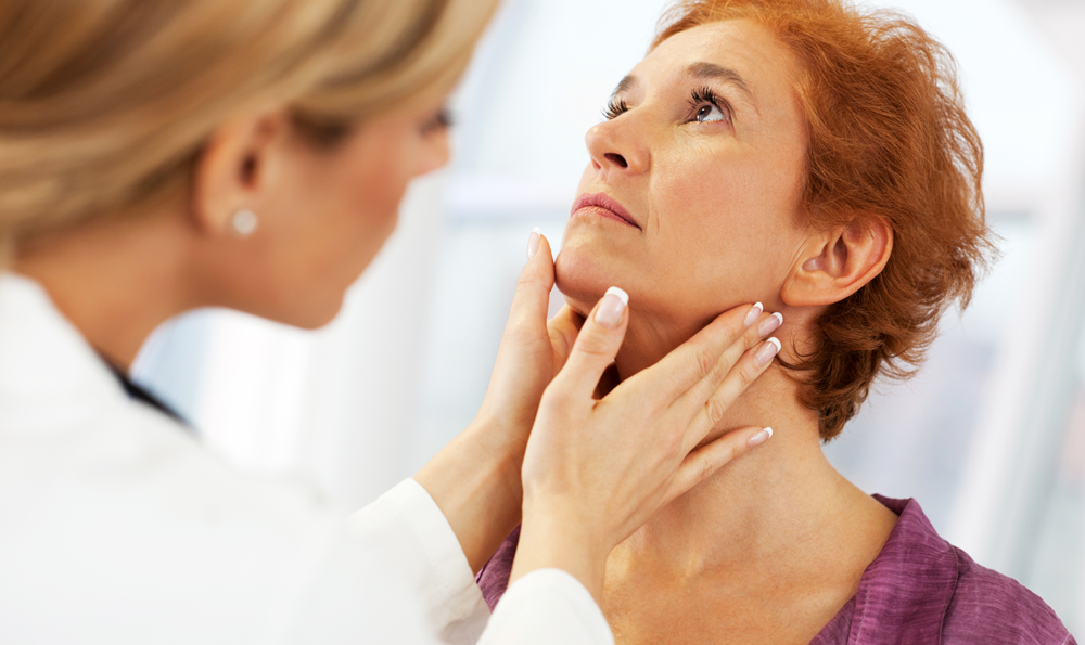 Mature woman getting a thyroid exam.
