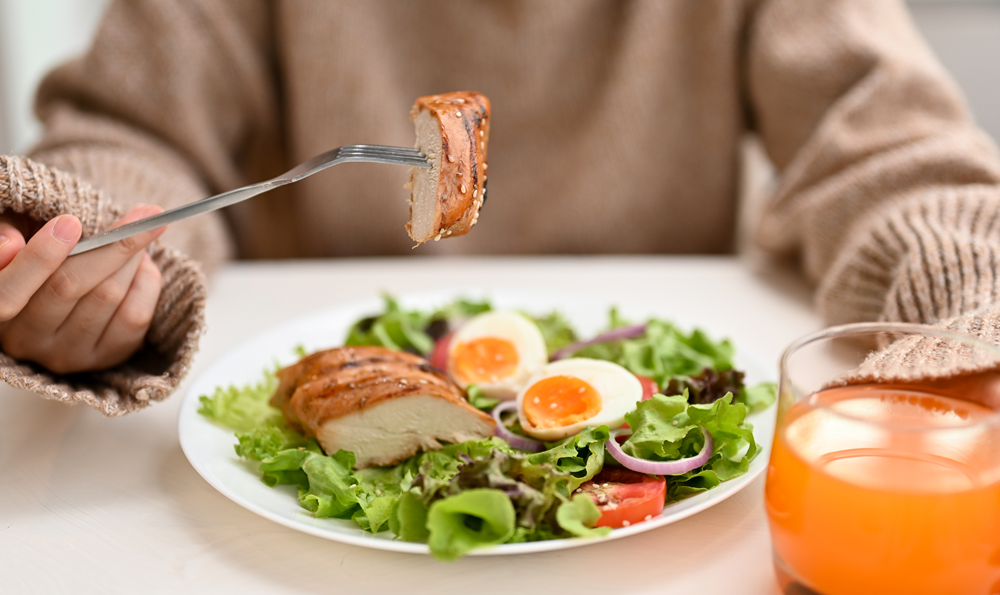 A woman eating a chicken and egg salad