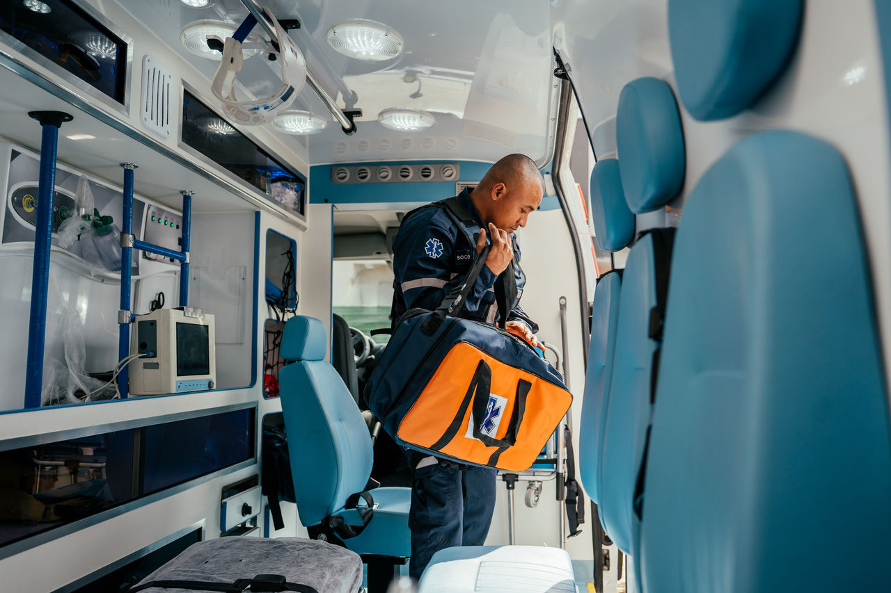 Paramedic retrieving first aid kit from ambulance.
