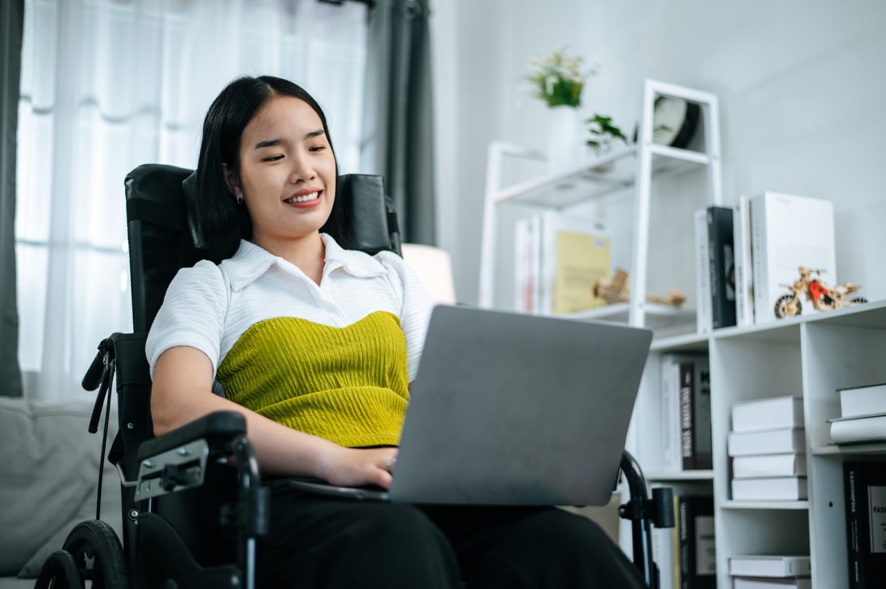 disabled-young-woman-sitting-in-wheelchair-using-laptop